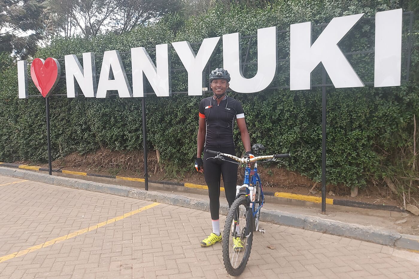 Radfahrer vor Plakat I love Nanyuki