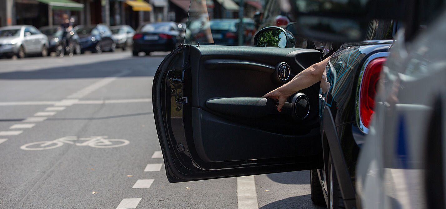 Plötzlich geöffnete Autotür im Straßenverkehr – typische Gefahrensituation für vorbeifahrende Radfahrende.